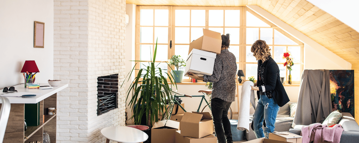 two people moving boxes in a living room.