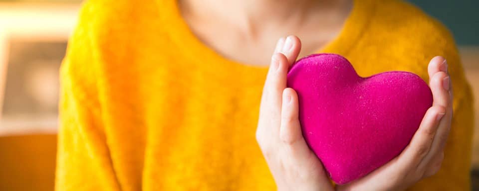 a woman holding a pink heart in her hands.
