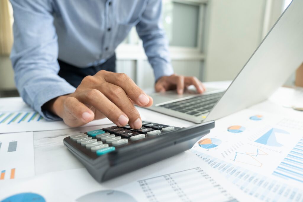 a man is using a calculator and a laptop.