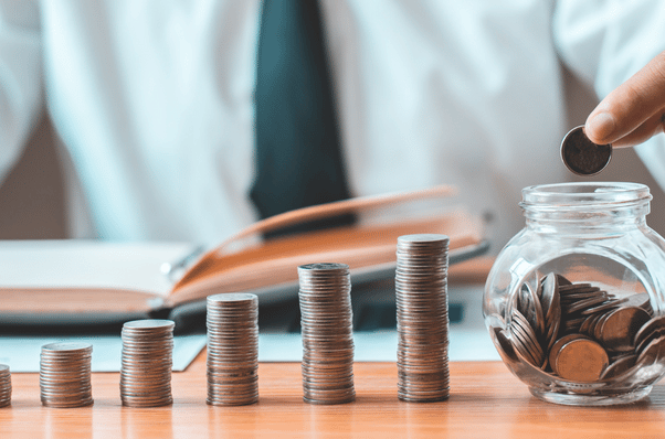 a person putting coins in a glass jar.
